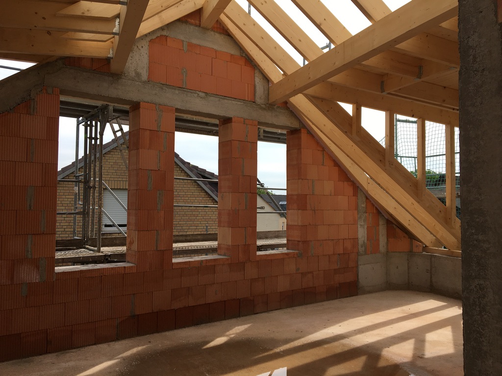 Holzdachkonstruktion über Mauerwerk und Stahlbetonbauteilen im Rohbau des Mehrfamilienhauses in Mainz